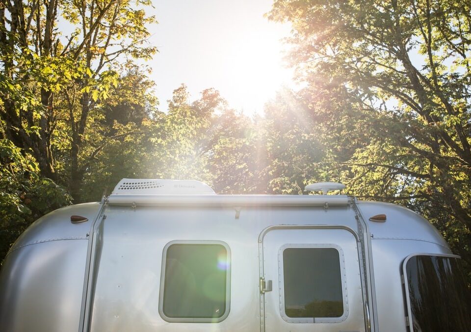 The Sun Shining Down on a Small Airstream Trailer Parked in the Woods
